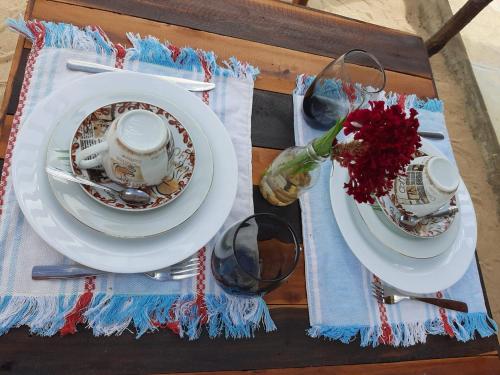 un tavolo con due piatti e tazze su un tavolo di Vila Vintém Chalés a Praia de Moitas