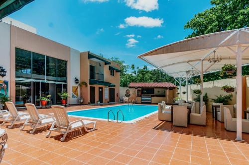 um pátio com piscina e cadeiras e uma casa em Hotel Siglo 21 Merida em Mérida
