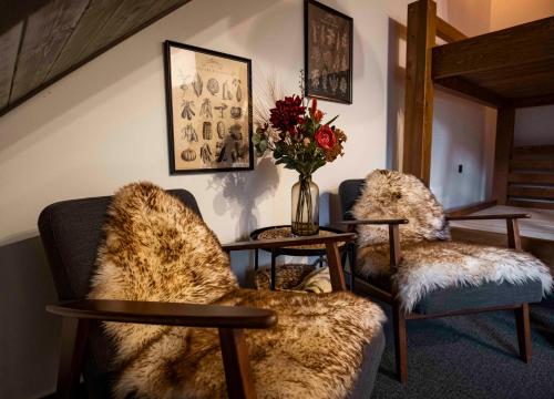 a living room with two chairs and a vase of flowers at Penzión u Sysľa in Muráň