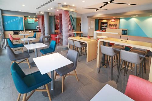 a restaurant with white tables and chairs and colorful chairs at avid hotel - Fresnillo by IHG in Fresnillo de González Echeverría