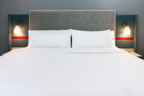 a large white bed with two pillows and two lights at avid hotel - Fresnillo by IHG in Fresnillo de González Echeverría