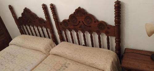 a bed with a wooden head board with two pillows at Hospedaje Octavio in Santillana del Mar