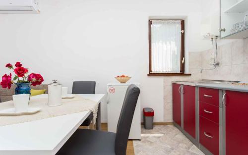 a kitchen with red cabinets and a table with flowers on it at Apartment in Silo/Insel Krk 13496 in Šilo
