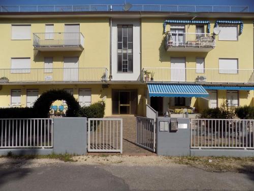 ein gelbes Gebäude mit einem weißen Zaun davor in der Unterkunft Apartment in Eraclea Mare 25161 in Eraclea Mare