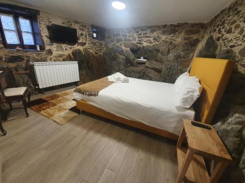 1 dormitorio con cama y pared de piedra en Casa do Talasnal Montanhas de Amor, en Lousã