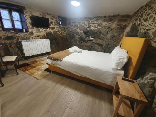 a bedroom with a bed and a stone wall at Casa do Talasnal Montanhas de Amor in Lousã