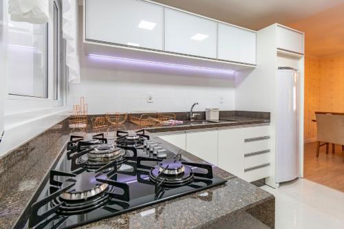 a kitchen with a black stove top oven at 2 dorm Rua Coberta de Canela @stayhousetemporada in Canela