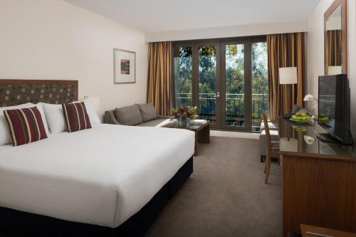 Pokój hotelowy z dużym łóżkiem i telewizorem w obiekcie Yarra Valley Lodge w mieście Wonga Park