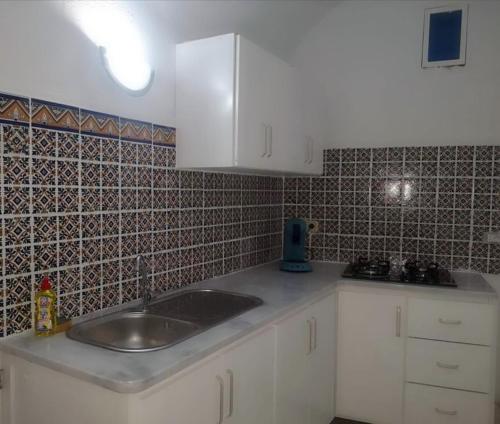 eine Küche mit einem Waschbecken und einer gefliesten Wand in der Unterkunft Nouveau Bungalow Djerba in Houmt Souk
