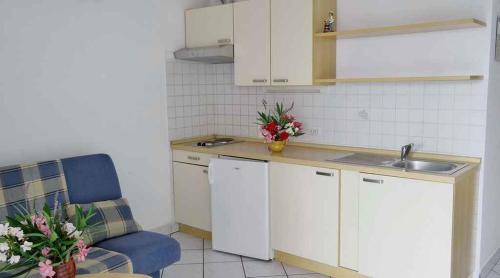 a kitchen with white cabinets and a sink and a blue chair at Apartment Silo 3 in Šilo