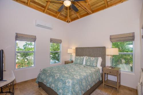 um quarto com uma cama e duas janelas em Tortuga Terrace-43 Lawson Rock Home em Roatán