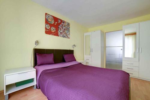 ein Schlafzimmer mit einem großen lila Bett in einem Zimmer in der Unterkunft Apartment Pula 15 in Vintijan