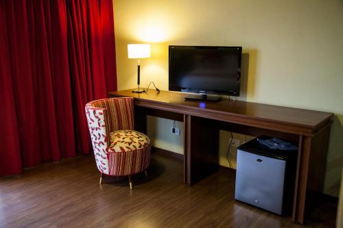 a room with a desk with a television and a chair at First Palermo Hotel in Buenos Aires