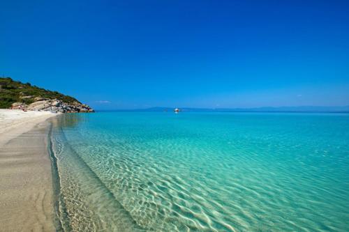 uma praia com água turquesa e um céu azul em Ktima Panagias em Ormos Panagias