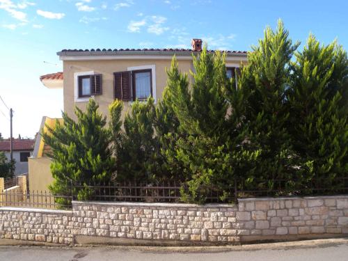a house with trees in front of a stone wall at Holiday home in Premantura - Istrien 10653 in Premantura