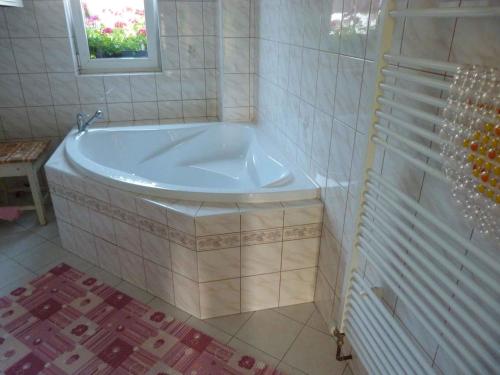 Holiday home Vrchlabi/Riesengebirge 2190 في Podhŭří: حوض استحمام أبيض في حمام مع نافذة