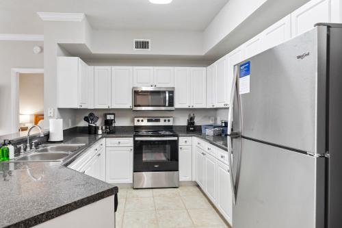 a kitchen with white cabinets and a stainless steel refrigerator at Kasa Wellington South Florida in Wellington