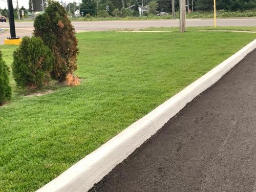 a curb next to a field of grass next to a street at Trunk Road Motel in Sault Ste. Marie