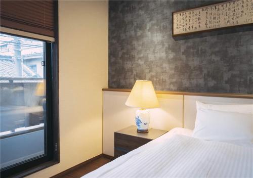 a bedroom with a bed with a lamp and a window at 谷町君・星屋・城下の宿 in Kyoto