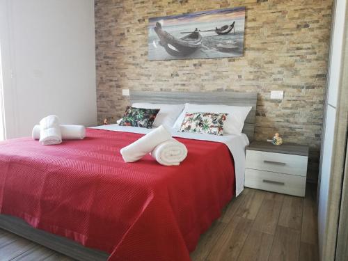 a bedroom with a red bed with a brick wall at Casa Veronica in Marzamemi