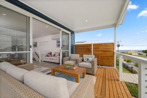 a living room with a couch and chairs on a balcony at Zion By The Sea - Aldinga Beach - C21 SouthCoast Holidays in Aldinga Beach