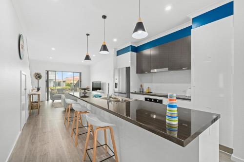 a kitchen with a long counter with stools at Zion By The Sea - Aldinga Beach - C21 SouthCoast Holidays in Aldinga Beach