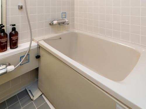 a white bath tub in a bathroom with a sink at Hotel Sunny Shiga in Yamanouchi