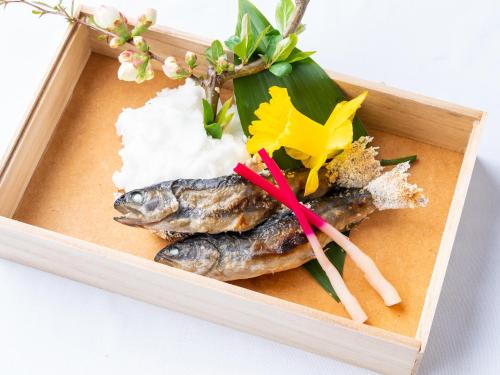 a wooden tray with three fish and rice at Hotel Sunny Shiga in Yamanouchi