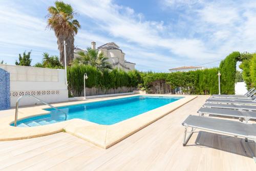 una piscina con sillas y una casa en Villa Caleta - Costa CarpeDiem en Calpe