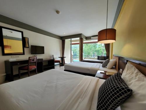 a bedroom with two beds and a desk and a television at Aekpailin River Kwai Resort in Kanchanaburi