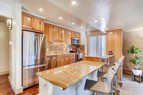 a kitchen with wooden cabinets and a stainless steel refrigerator at Hot Tub & Sauna PEAK 8 BRECKENRIDGE in Breckenridge