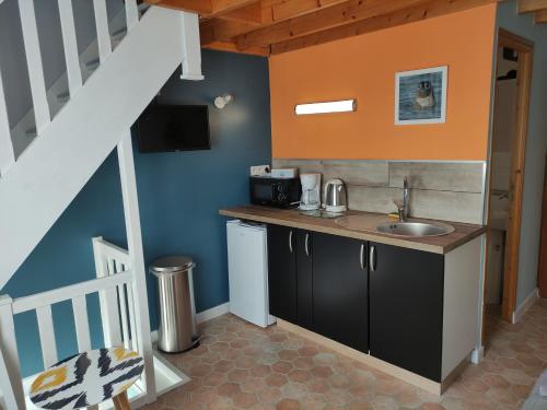 une cuisine avec un évier et un escalier dans l'établissement L'Anse Noire, à Saint-Valery-sur-Somme