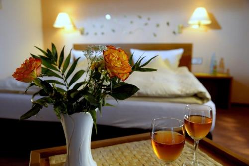 a table with two glasses of wine and a vase with flowers at Garni Hotel & Ferienwohnungen Seeschlößchen in Waldeck
