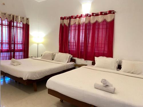 twee bedden in een kamer met rode gordijnen bij Le Royce Private Villa in Pondicherry