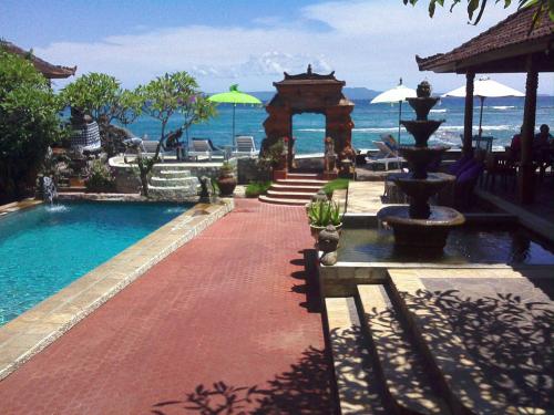 a resort with a swimming pool and a fountain at Puri Oka Beach Bungalows in Candidasa