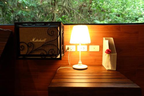 a lamp sitting on a table next to a window at Namtok Sarika Resotel in Nakhon Nayok