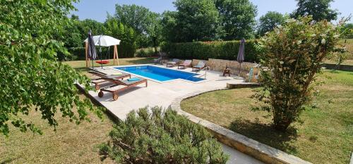 a swimming pool with chairs and an umbrella in a yard at Sunny Garden Villa with Pool in Loborika