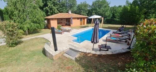 a pool with chairs and an umbrella next to a house at Sunny Garden Villa with Pool in Loborika