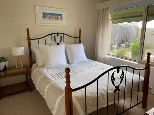 a bedroom with a bed with white pillows and a window at The Esplanade Holiday Home in Indented Head