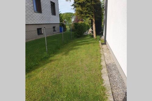 a grassy yard next to a house with a fence at Comfy Plaza 