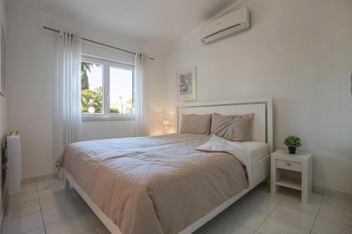 a white bedroom with a large bed and a window at Villa Sagres in Portimão