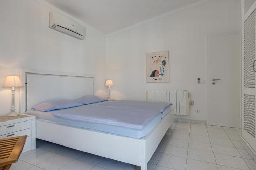 a white bedroom with a large bed with blue sheets at Villa Sagres in Portimão