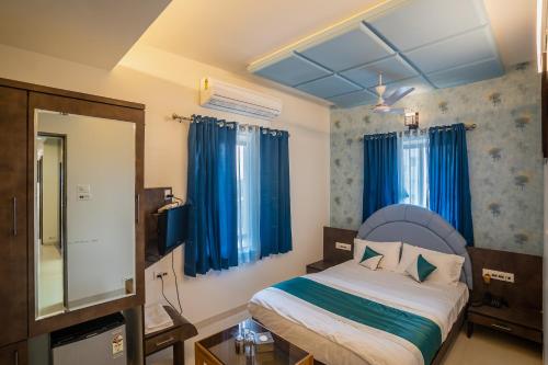 a bedroom with a bed with blue curtains and a mirror at Hotel New Panchratna in Ahmadnagar