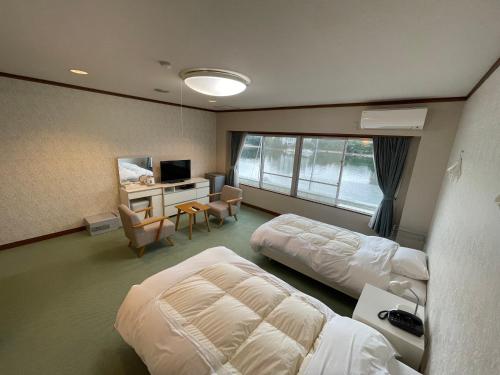 白浜町にあるマリーナホテル海空のベッド2台、デスク、テレビが備わるホテルルームです。