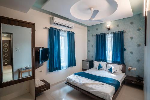 a bedroom with a bed with blue curtains and a mirror at Hotel New Panchratna in Ahmadnagar