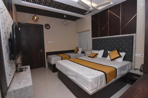 a hotel room with two beds and a television at Hotel Atlantis in Kumbakonam