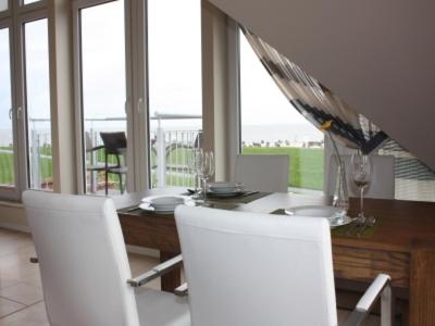 a dining room with a table and white chairs at BadeWerk Appartements in Neuharlingersiel
