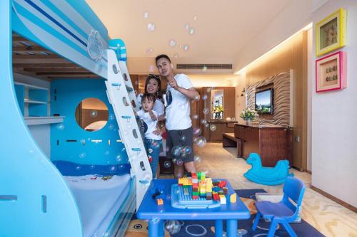 a man and two children standing in a play room at Mission Hills Hotel Resorts Dongguan in Dongguan