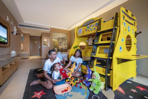 a man and two children in a room with a bunk bed at Mission Hills Hotel Resorts Dongguan in Dongguan