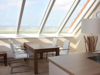 a room with a table and chairs and a large window at BadeWerk Appartements in Neuharlingersiel